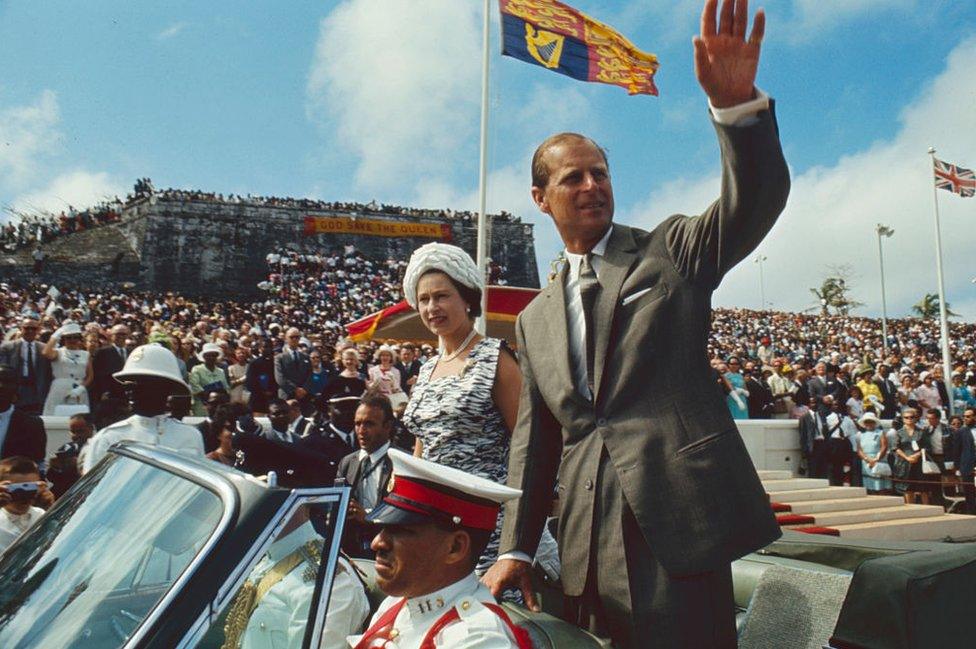Prince Phillip and Queen Elizabeth waving at an audience. They are known for their powerful reputation.